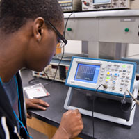 Student adjusting electronics equipment